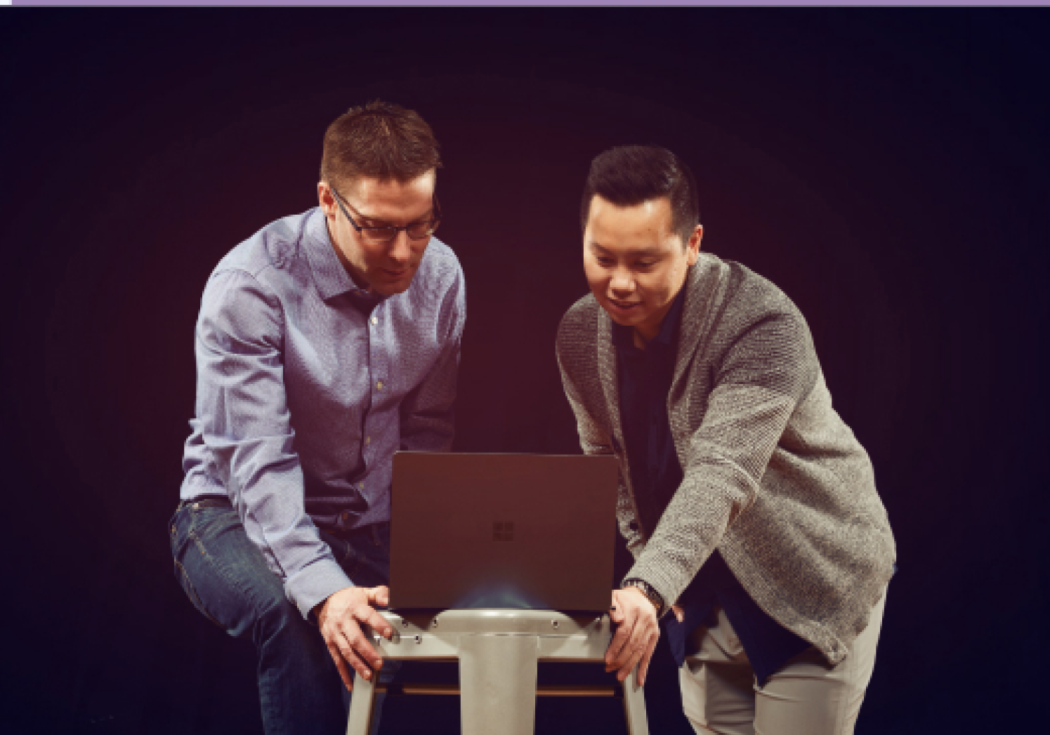 Two colleagues reviewing work on a laptop