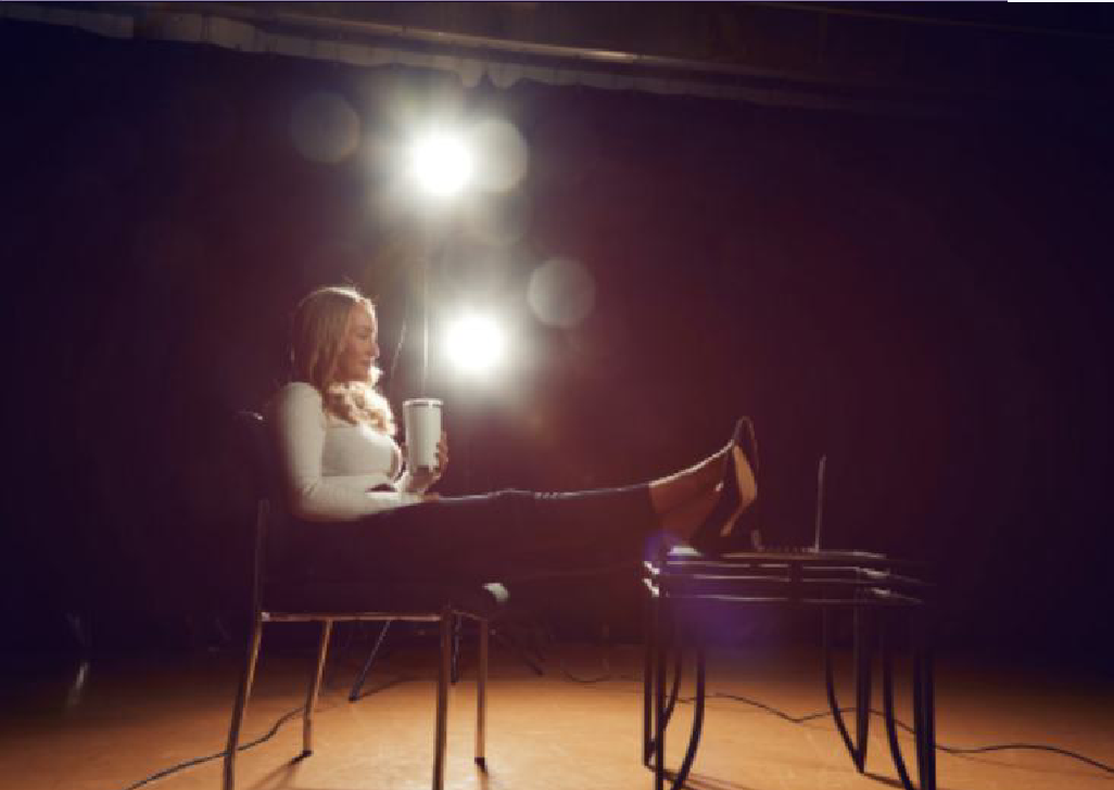 A person seated at a desk under dramatic studio lighting